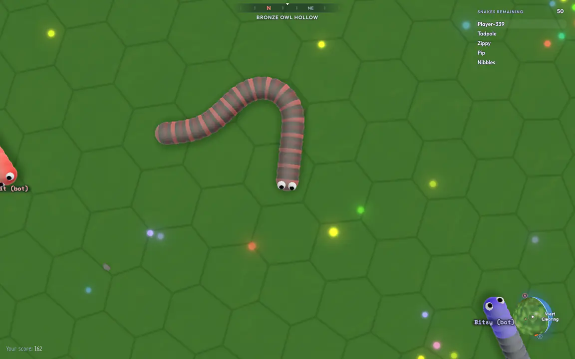 A Battle Royale game seen from above: a striped snake curving across green hexagon ground, glowing pellets, other snakes, a compass at the top, a list of snakes left in the top right and a minimap in the bottom right